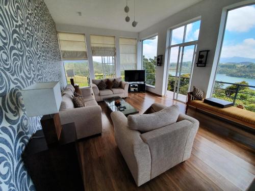 a living room with couches and a tv and windows at Tranquil Villa in Nuwara Eliya