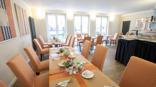 een eetkamer met tafels, stoelen en ramen bij Hotel Elite in Karlsruhe