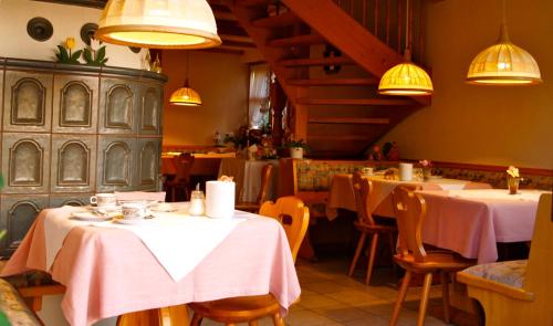 um restaurante com mesas brancas, cadeiras e luzes em Landhaus Lena em Schönwald