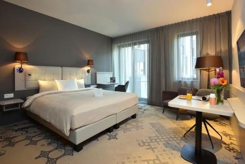 Pokój hotelowy z dużym łóżkiem i biurkiem w obiekcie Martin's Louvain-la-Neuve w mieście Louvain-la-Neuve