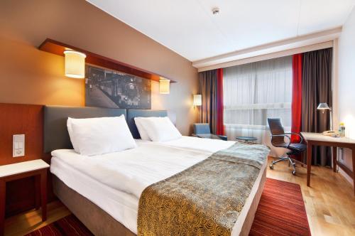 a hotel room with a large bed and a desk at Holiday Inn Tampere - Central Station by IHG in Tampere