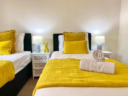 Spacious 5 bed townhouse Manchester, Salford Qauys - Two Bedroom with Parking في مانشستر: غرفة نوم بسريرين بملاءات صفراء ومخدات صفراء