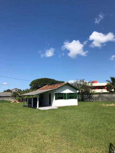 una pequeña casa blanca en un campo de hierba en A Casinha en Florianópolis