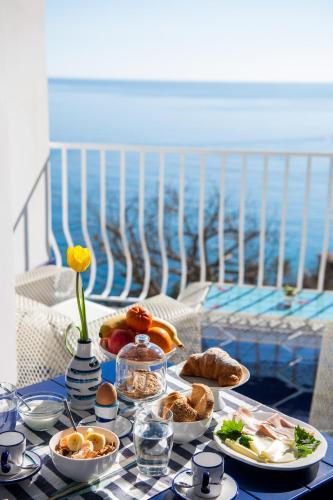 a table with plates of food on a table with the ocean at Imperati Suites by Alcione Residence in Positano