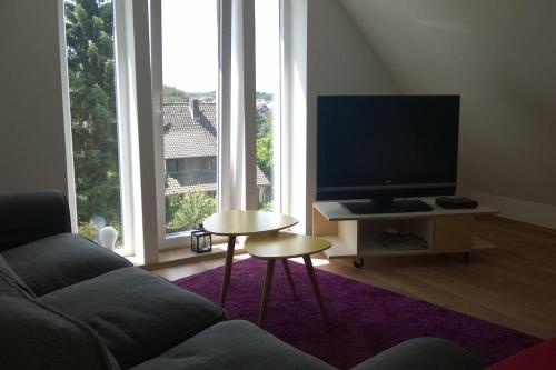 uma sala de estar com um sofá, uma televisão e uma mesa em Ferienwohnung Ostercappeln em Ostercappeln
