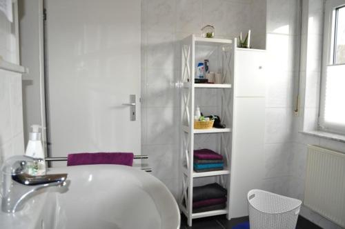 a white bathroom with a sink and a shelf at Bramwaldblick in Hannoversch Münden