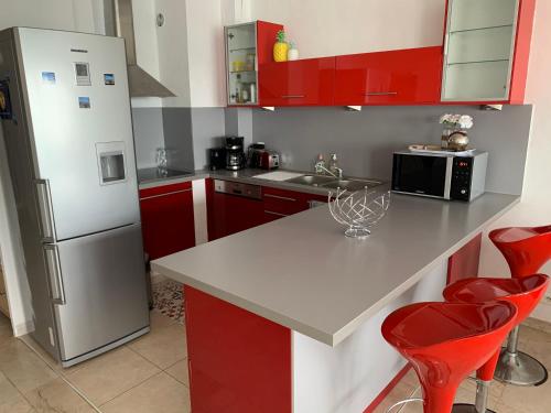 une cuisine avec des armoires rouges et un réfrigérateur blanc dans l'établissement Bandol le grand horizon, à Bandol