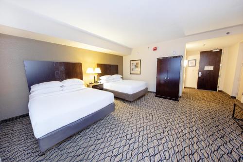 a hotel room with two beds and a bathroom at Holiday Inn St. Louis Airport West Earth City by IHG in Earth City