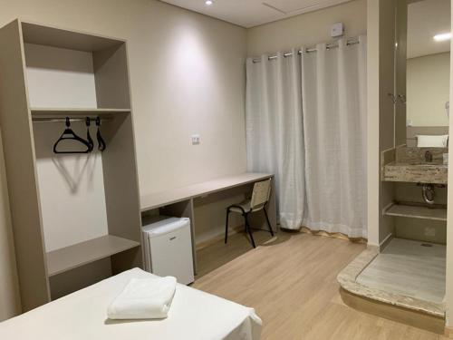 a bathroom with a sink and a desk in a room at Hotel Arlen in Pouso Alegre