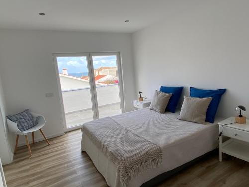 a bedroom with a bed and a large window at FamilyHost Charm Porto Covo in Porto Covo