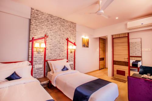 1 dormitorio con 2 camas y pared de ladrillo en Hotel Prabha Palace, en Ahmadnagar