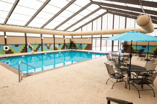 a swimming pool with a table and chairs and a table and umbrella at Holiday Inn St. Louis Airport West Earth City by IHG in Earth City