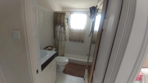 a bathroom with a tub and a toilet and a shower at JersonApartments in Christ Church