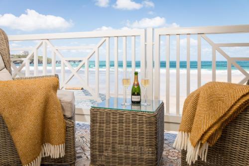 a table with two glasses of wine on a balcony at Tolcarne Beach Colonial Restaurant and Rooms in Newquay