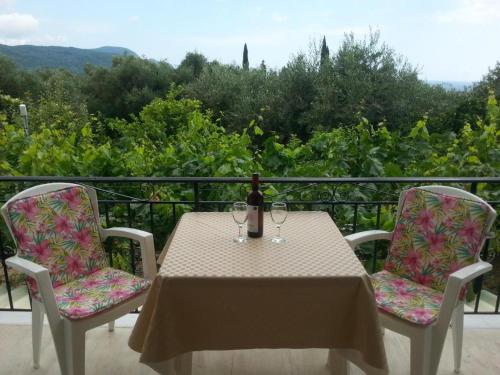 a table with a bottle of wine and two chairs at Katerina Studios in Paleokastritsa