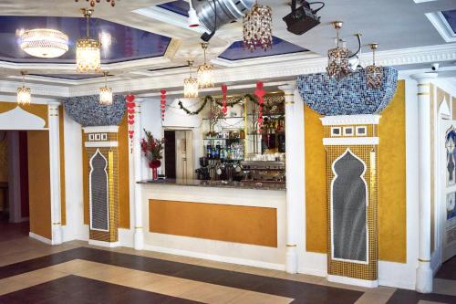 a bar in a restaurant with yellow walls and chandeliers at Східний in Brzezhany