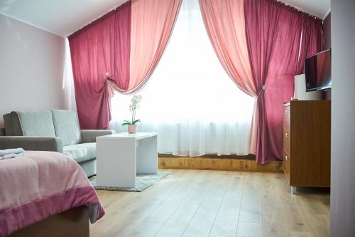 a bedroom with a bed and a window with pink curtains at Східний in Brzezhany