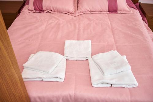 a bed with pink sheets and white towels on it at Східний in Brzezhany