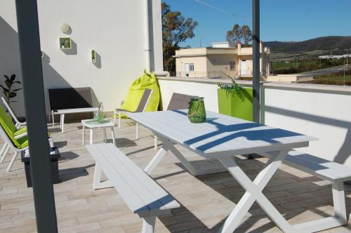 a white table and bench on a balcony at Le casette di Frà al Bondì in Santa Severa