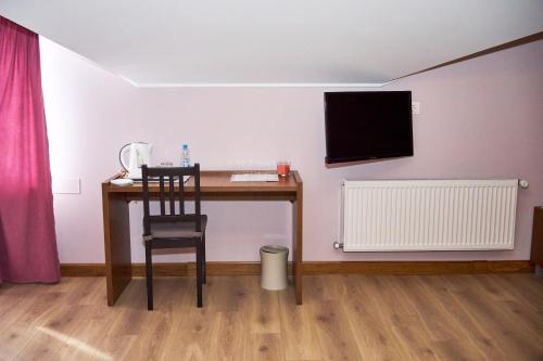 a desk with a chair and a television on a wall at Східний in Brzezhany
