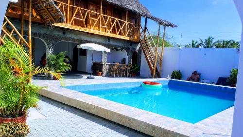 a swimming pool in front of a building with a house at Hostal Villa Brisa in Ballenita