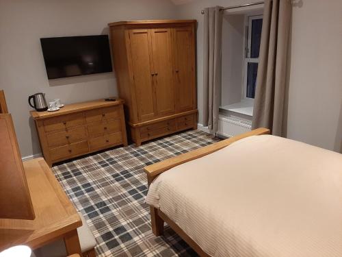 a bedroom with a bed and a dresser and a television at Fountain Cottage Cafe and B&B in Bellingham