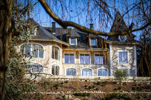 a large stone house with a large roof at Hôtel L'Incomparable Aix-Les-Bains in Tresserves