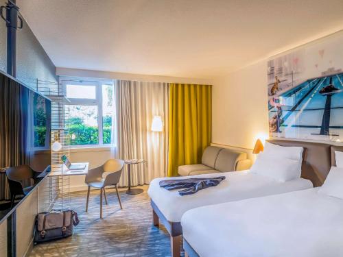 a hotel room with two beds and a couch at Novotel Paris Créteil Le Lac in Créteil