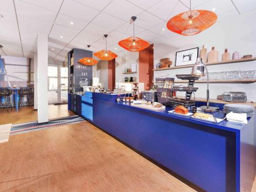 a restaurant with a blue counter with food on it at ibis Styles Toulouse Lavaur in Lavaur
