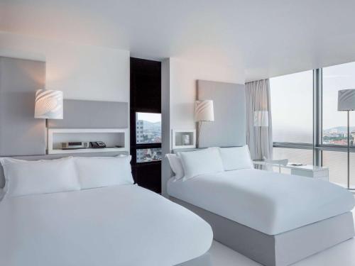 a white bedroom with two beds and a window at SO/ Vienna in Vienna