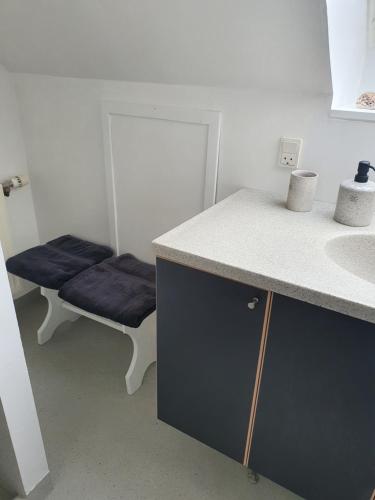 a bathroom with a counter and a sink and a bench at Ferie Lejligheden Landlyst in Rødvig