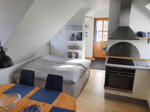 a bedroom with a bed and a kitchen with a stove at Ferie Lejligheden Landlyst in Rødvig
