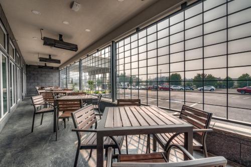 a cafeteria with wooden tables and chairs and large windows at Holiday Inn Tacoma Mall by IHG in Tacoma