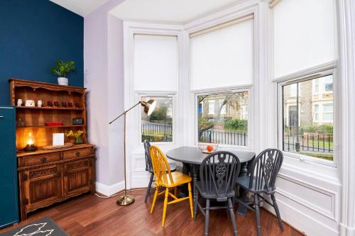a dining room with a table and chairs and windows at Lovely Abode in Newcastle - Ground Floor in Newcastle upon Tyne