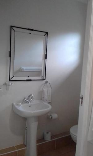 a white bathroom with a sink and a mirror at Marlin Cottage in Chintsa