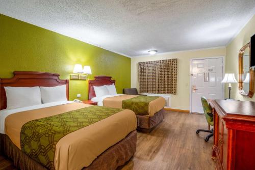 a hotel room with two beds and a desk at Rodeway Inn & Suites Fort Jackson in Columbia
