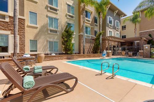 a swimming pool with two lounge chairs next to a building at Comfort Inn & Suites Near Ontario Airport in Ontario