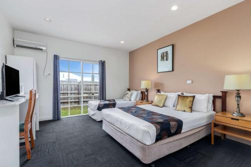 a hotel room with two beds and a television at Greensborough Motel in Melbourne