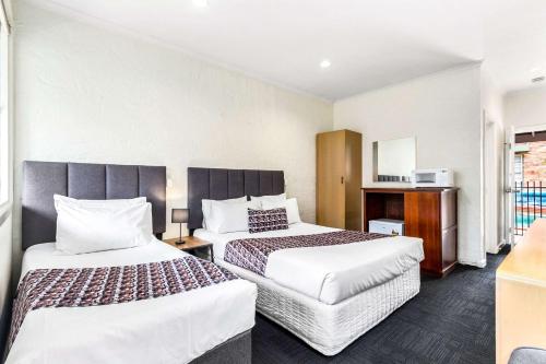 a hotel room with two beds and a kitchen at Greensborough Motel in Melbourne