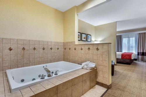 a large bathroom with a tub and a bedroom at Comfort Suites South in Elkhart