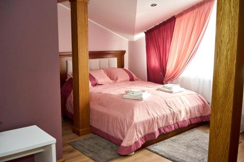 a bedroom with a bed with pink sheets and a mirror at Східний in Brzezhany
