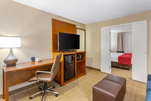 a hotel room with a desk with a television and a bed at Comfort Suites Oakbrook Terrace near Oakbrook Center in Oakbrook Terrace