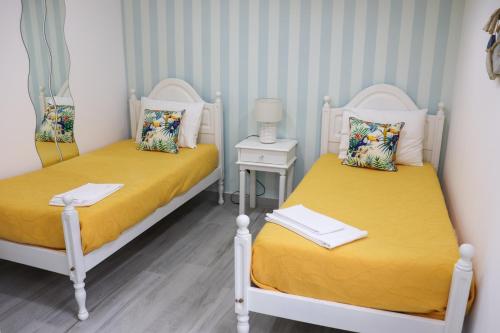 ナザレにあるFlipflops Apartments 3の小さな部屋のベッド2台 黄色いシーツ付