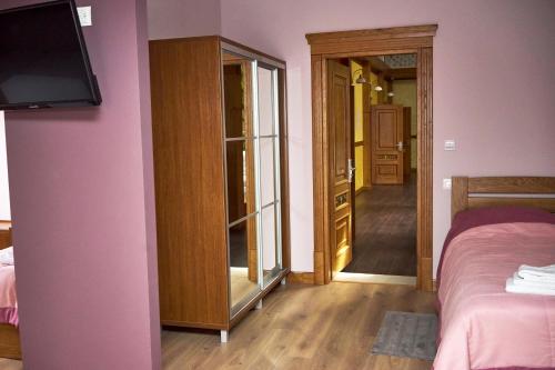 a bedroom with a pink wall with a bed and a tv at Східний in Brzezhany