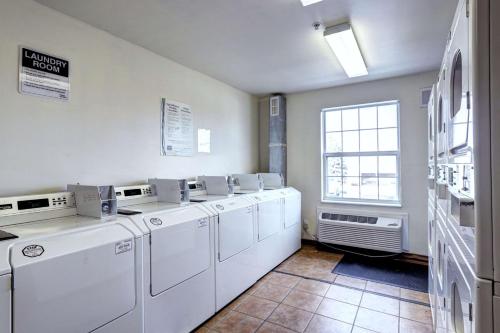 eine Waschküche mit weißen Waschmaschinen und einem Fenster in der Unterkunft Suburban Studios Westminster Denver North in Westminster