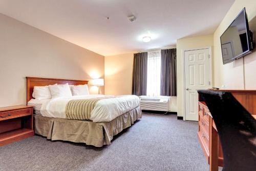a hotel room with a bed and a flat screen tv at Suburban Studios Westminster Denver North in Westminster