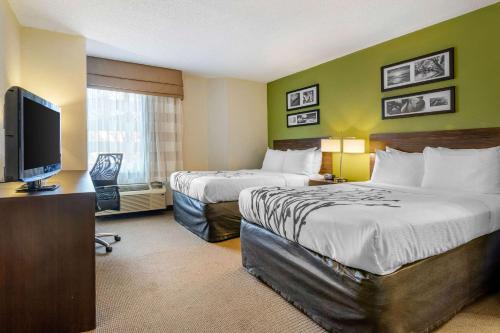 a hotel room with two beds and a flat screen tv at Sleep Inn I-95 North Savannah in Port Wentworth