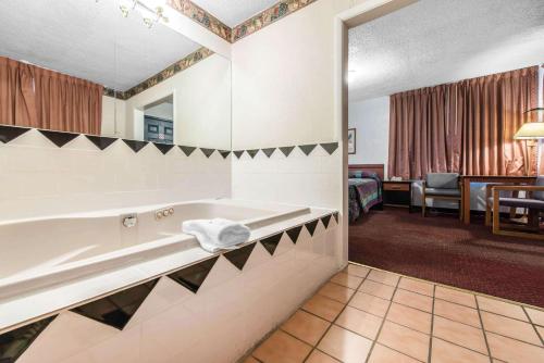a hotel bathroom with a tub and a room at Rodeway Inn & Suites Colorado Springs in Colorado Springs