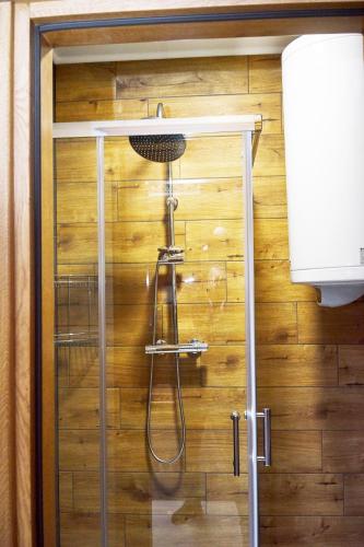 a shower in a bathroom with a wooden wall at Східний in Brzezhany