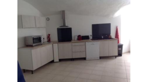 une cuisine avec des armoires blanches et un micro-ondes dans l'établissement gite de l'église, à Laroque